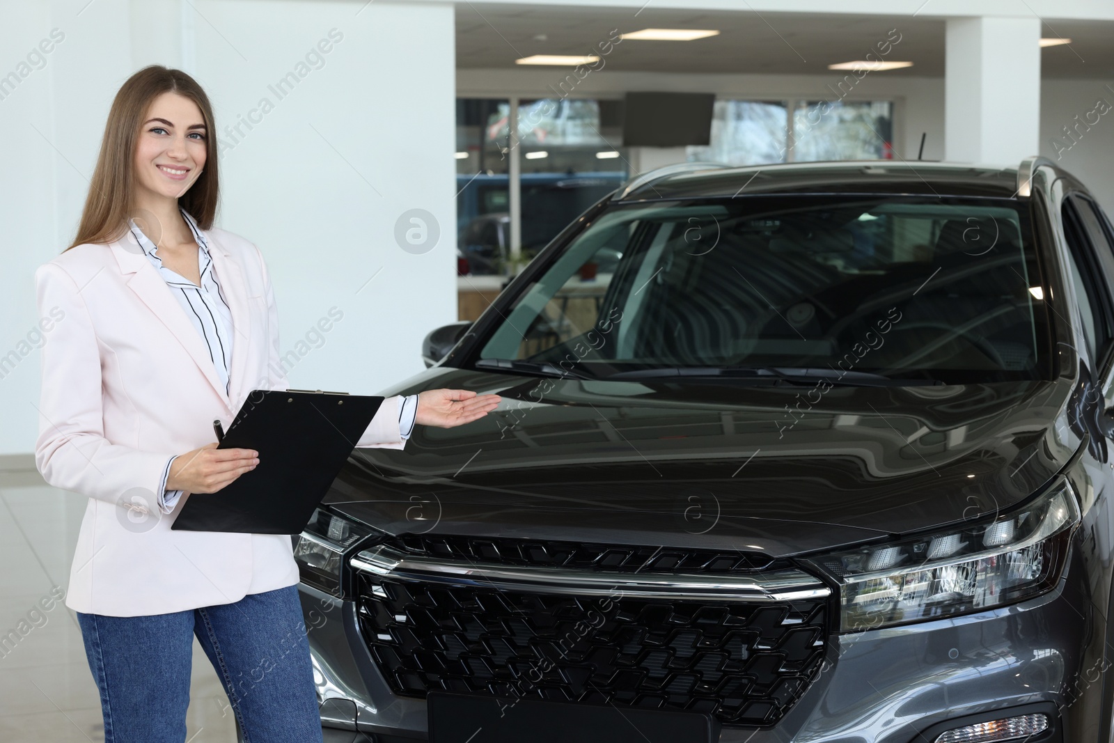 Photo of Happy saleswoman near new black car in salon