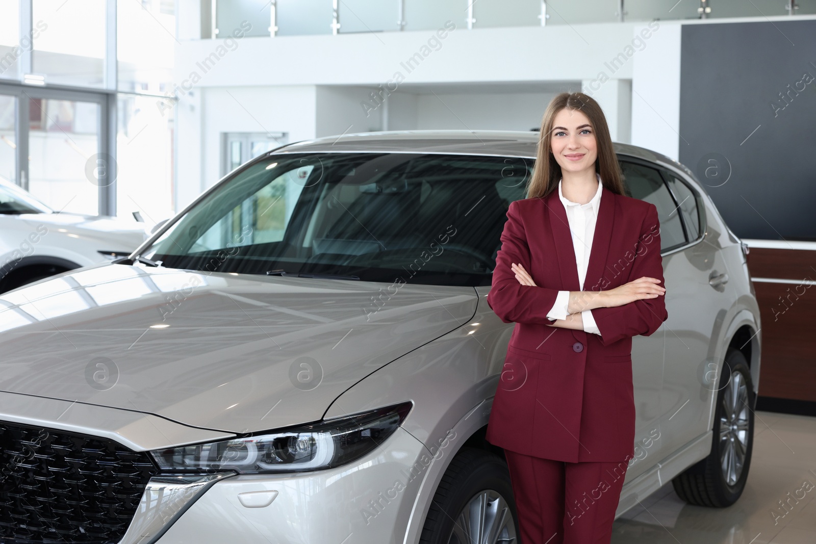 Photo of Happy saleswoman near new silver car in salon