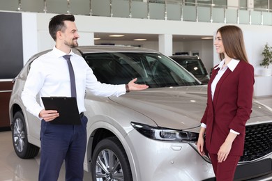 Photo of Salesman and client near new car in salon