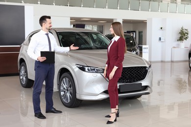 Photo of Salesman and client near new car in salon