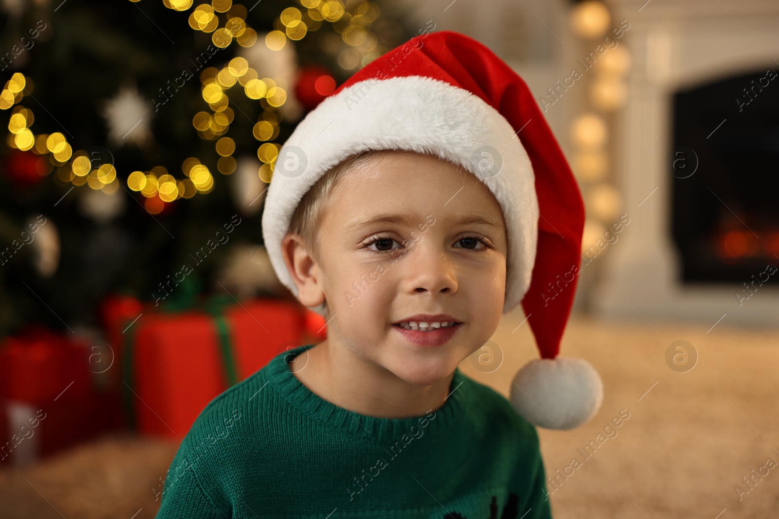 Photo of Cute little boy with Santa hat in room decorated for Christmas