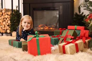 Photo of Little girl with Christmas gifts on floor at home