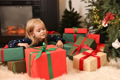 Photo of Little girl with Christmas gifts on floor at home