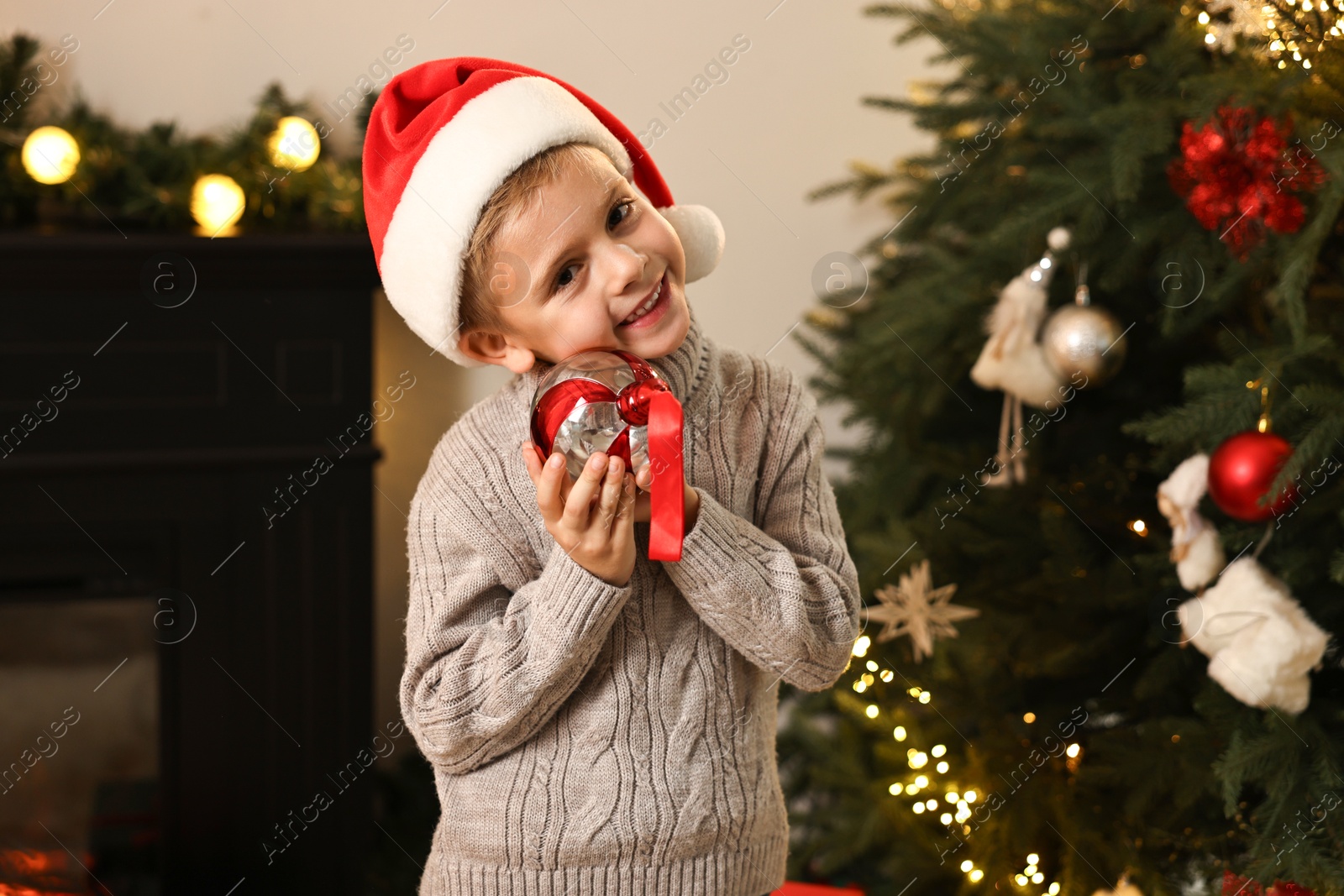 Photo of Little boy with Christmas ornament at home