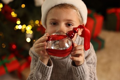 Photo of Little boy with Christmas ornament at home