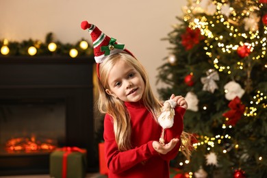 Photo of Little girl with Christmas ornament at home