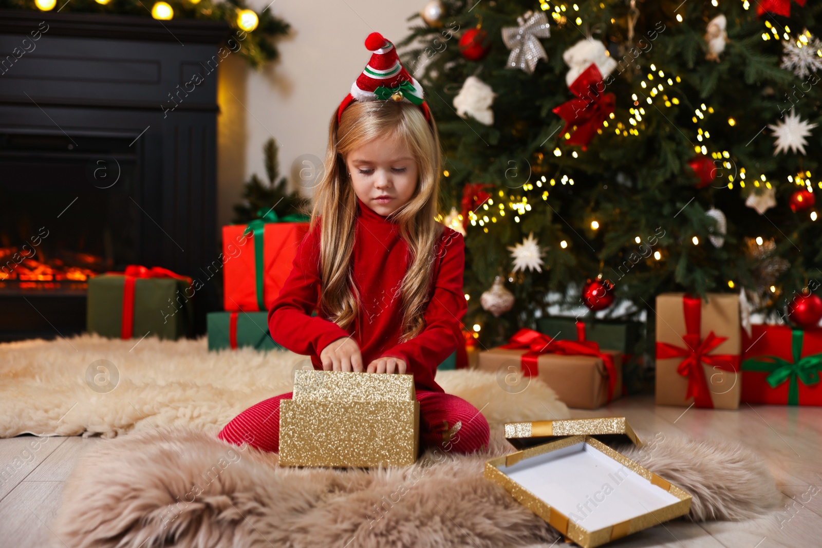 Photo of Little girl opening Christmas gift on floor at home