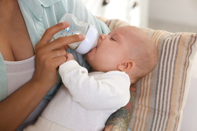 Photo of Mother feeding her cute baby indoors, closeup