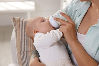 Photo of Mother feeding her cute baby indoors, closeup