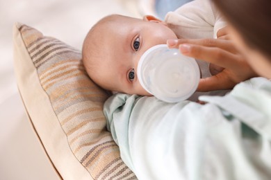 Photo of Mother feeding her cute baby indoors, closeup