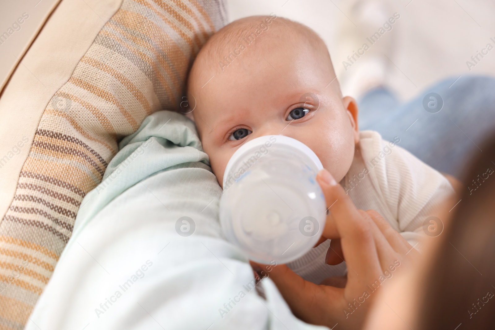 Photo of Mother feeding her cute baby indoors, closeup