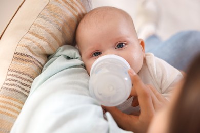 Photo of Mother feeding her cute baby indoors, closeup