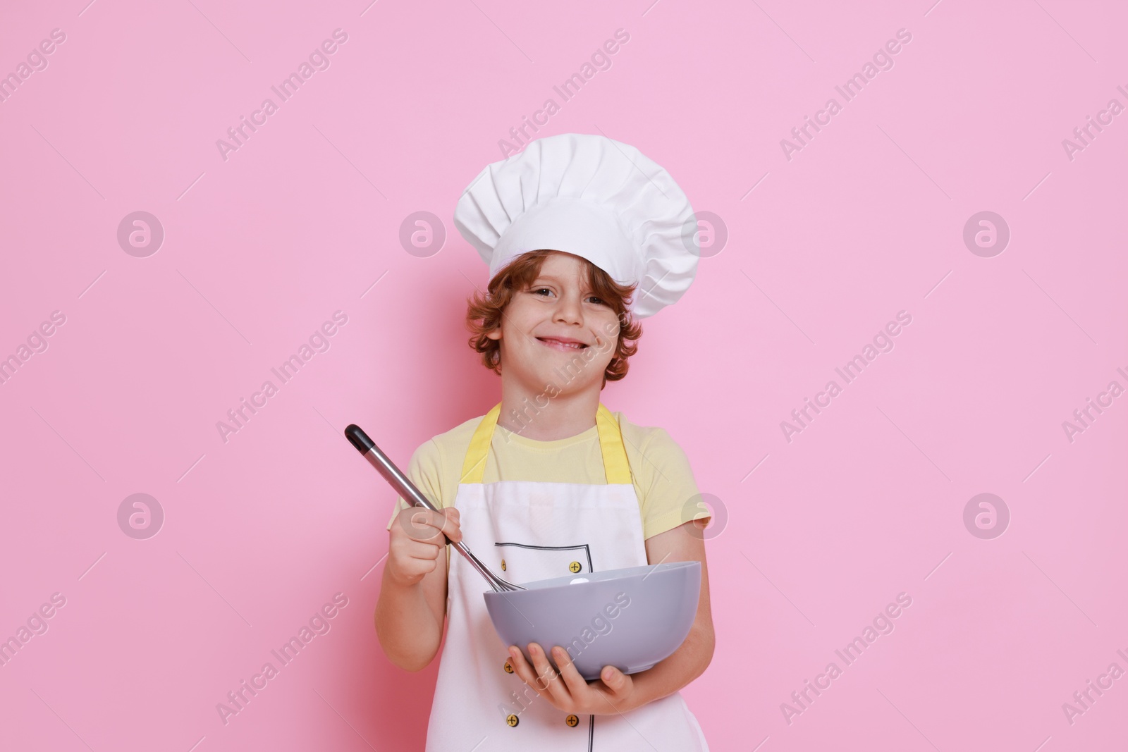 Photo of Little boy with bowl and whisk pretending to be chef on pink background. Dreaming about future profession