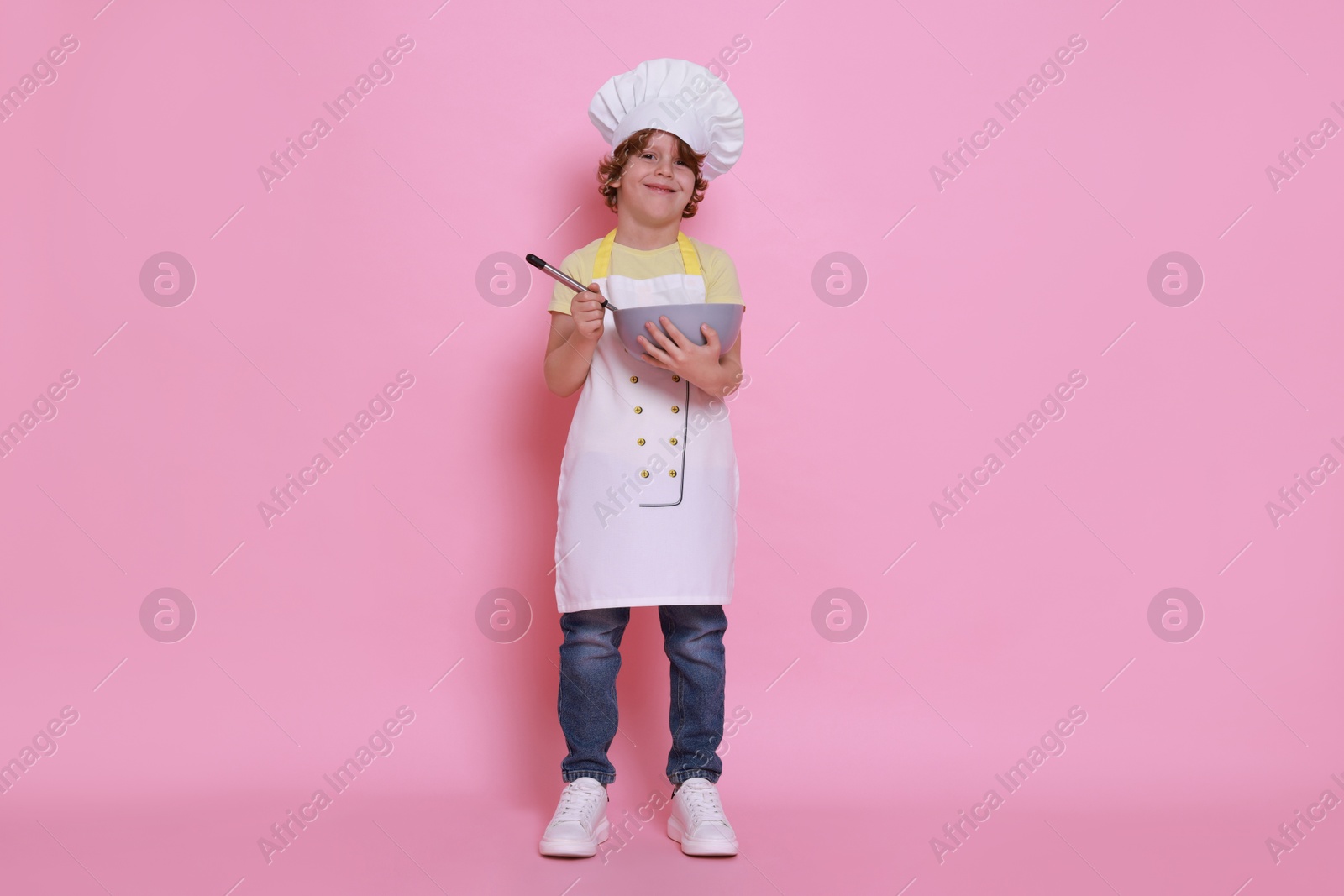 Photo of Little boy with bowl and whisk pretending to be chef on pink background. Dreaming about future profession