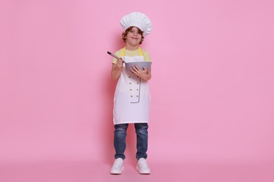 Photo of Little boy with bowl and whisk pretending to be chef on pink background. Dreaming about future profession