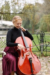 Photo of Beautiful young woman playing cello in park