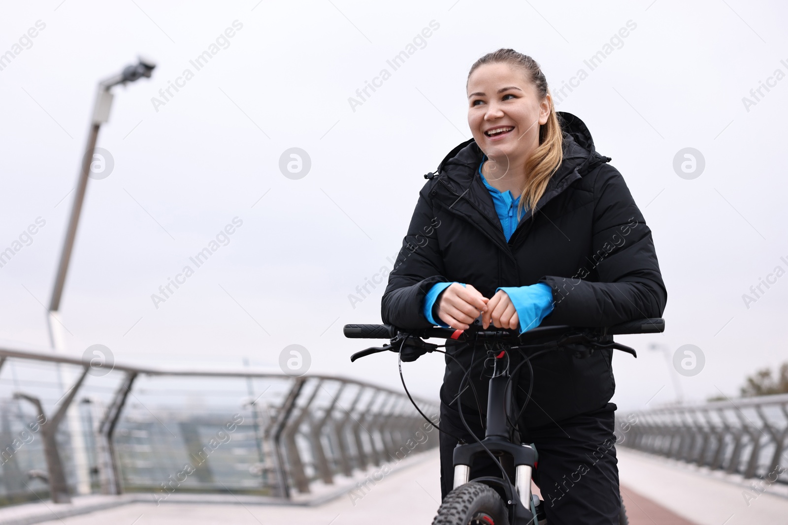 Photo of Woman with bicycle outdoors, space for text