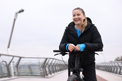 Photo of Woman with bicycle outdoors, space for text