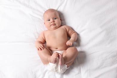 Photo of Cute little baby in diaper on bed, top view