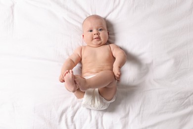 Photo of Cute little baby in diaper on bed, top view