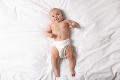 Photo of Cute little baby in diaper on bed, top view