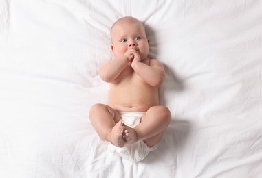 Photo of Cute little baby in diaper on bed, top view