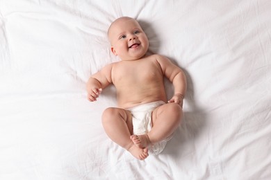 Photo of Cute little baby in diaper on bed, top view