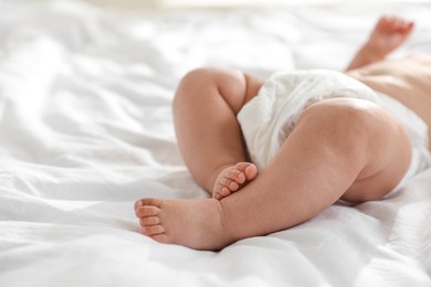 Photo of Cute little baby in diaper on bed, closeup