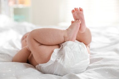 Photo of Cute little baby in diaper on bed indoors, closeup