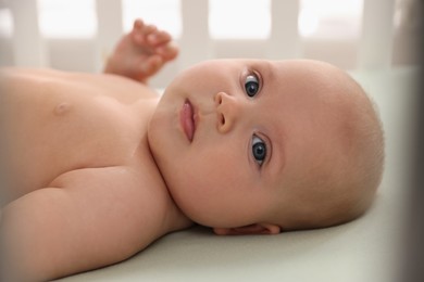 Photo of Cute little baby lying in crib indoors