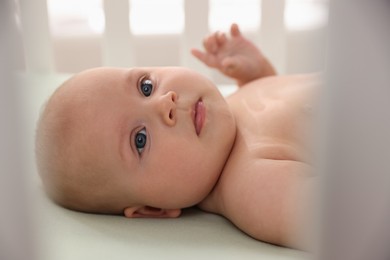 Photo of Cute little baby lying in crib indoors