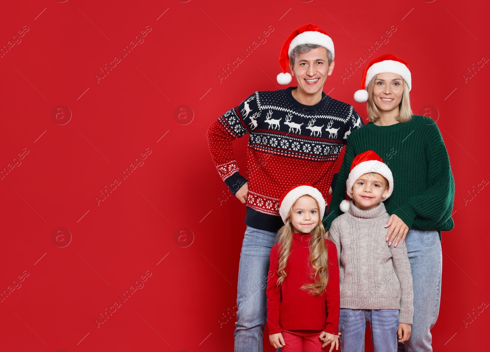 Photo of Happy family in Santa hats on red background. Christmas season