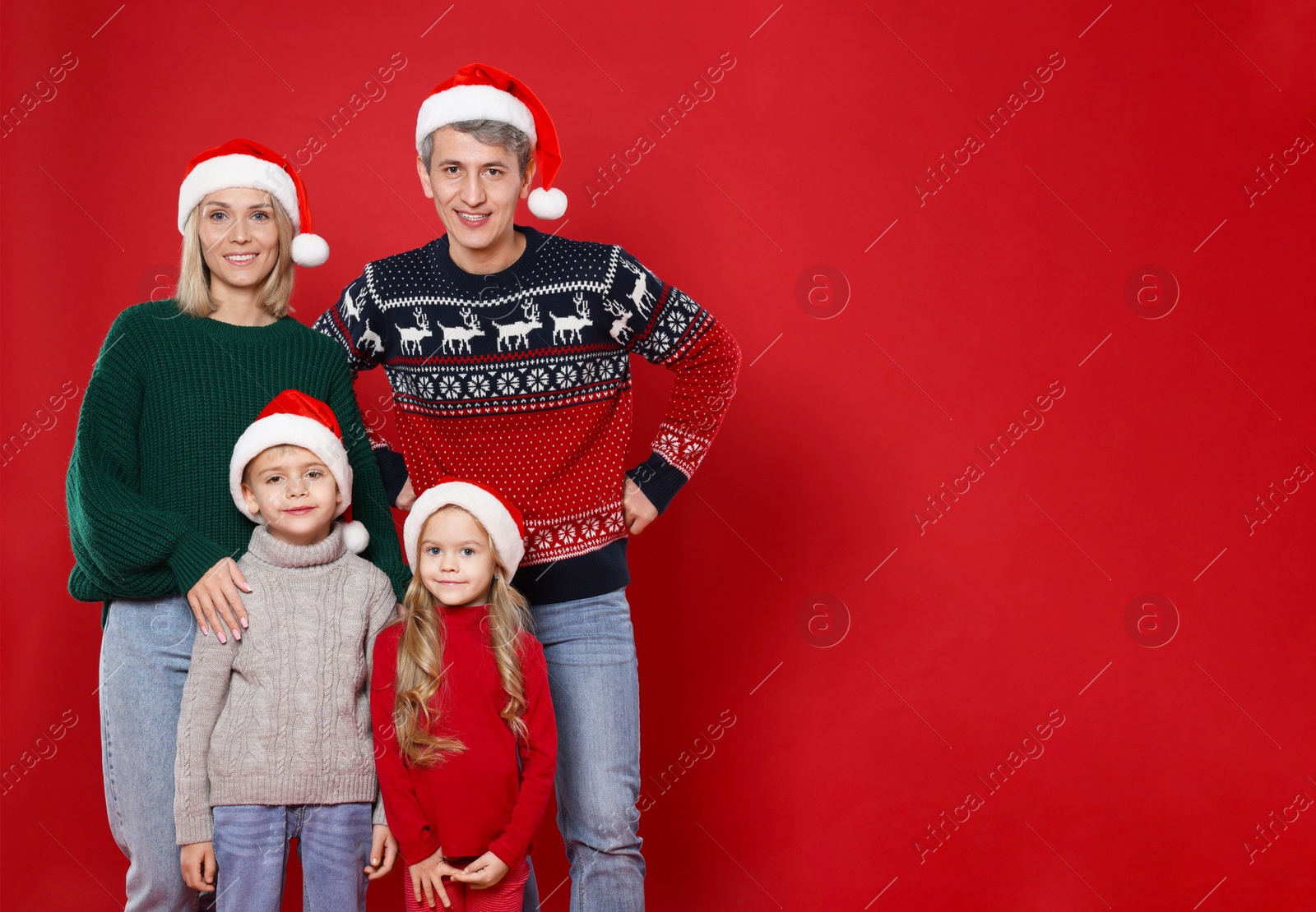 Photo of Happy family in Santa hats on red background. Christmas season