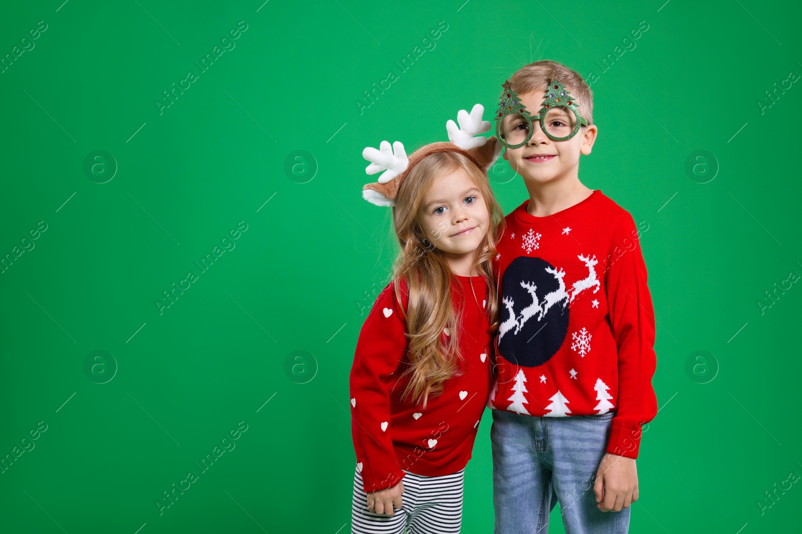 Photo of Cute little children in Christmas sweaters and accessories on green background. Space for text