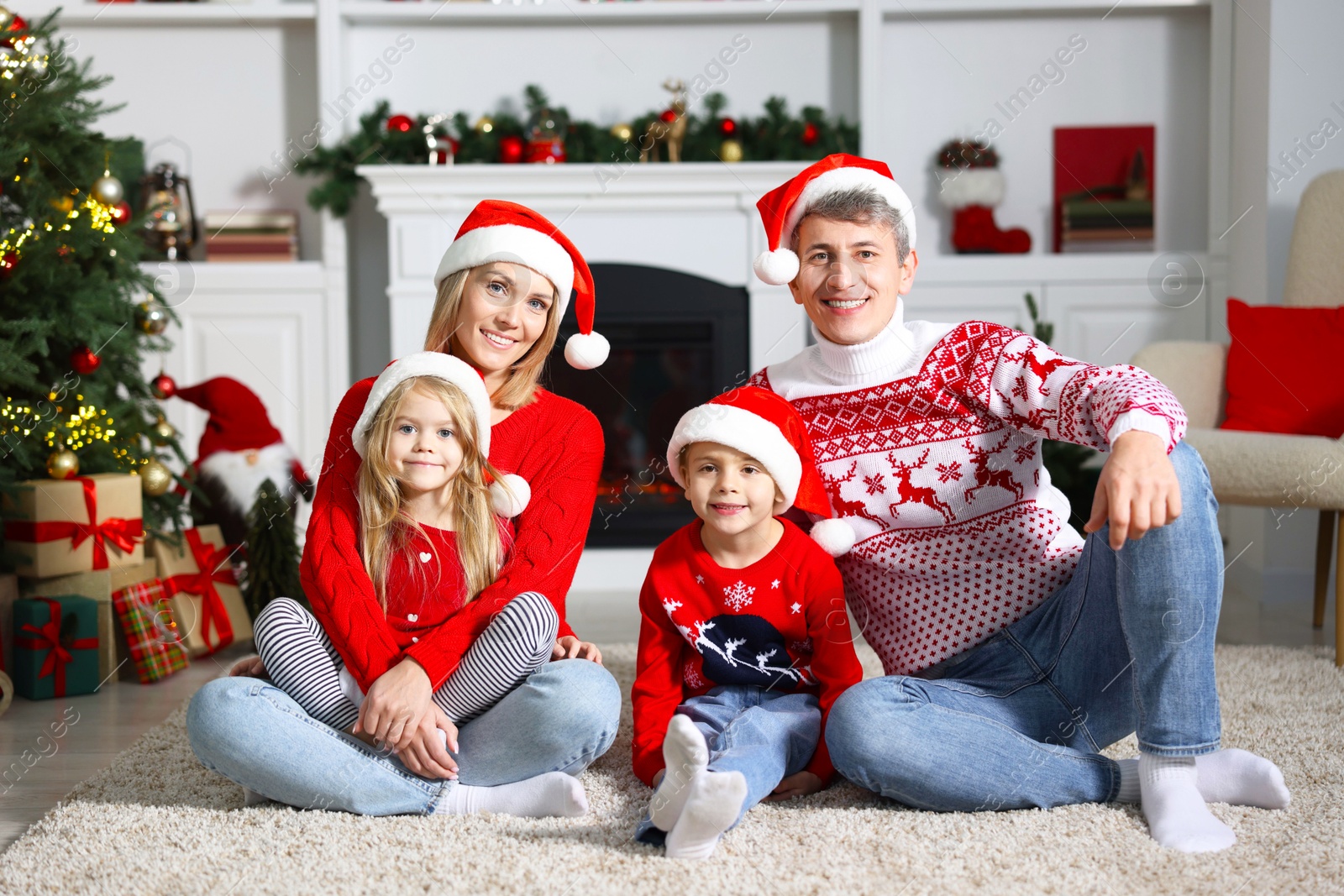 Photo of Lovely family in Christmas sweaters and Santa hats at home