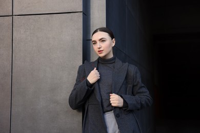 Photo of Beautiful young woman with black coat posing outdoors