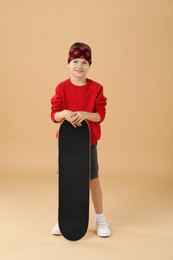 Photo of Little boy with skateboard on beige background