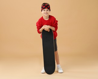 Photo of Little boy with skateboard on beige background