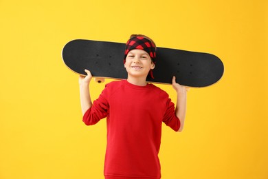 Photo of Little boy with skateboard on yellow background