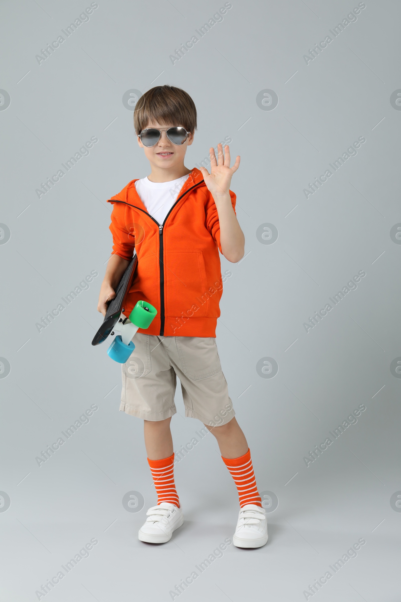 Photo of Little boy with skateboard on light grey background