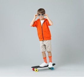 Little boy with skateboard on light grey background