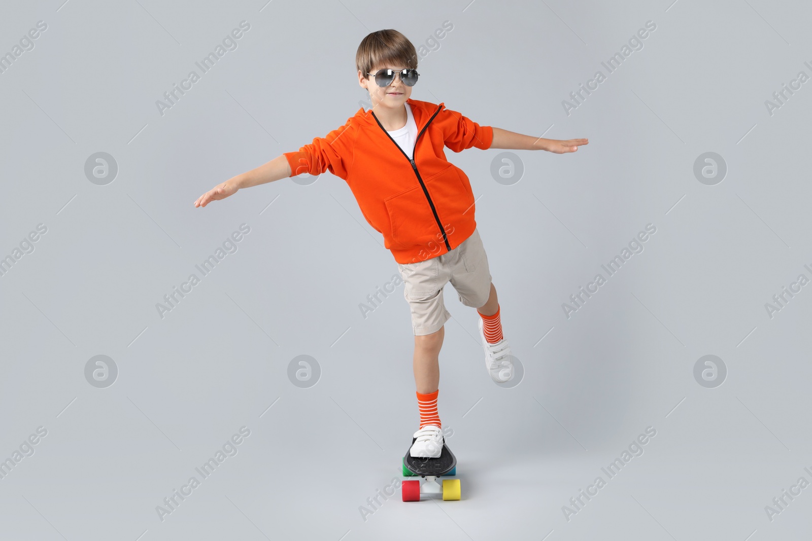 Photo of Little boy with skateboard on light grey background