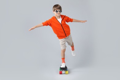 Photo of Little boy with skateboard on light grey background