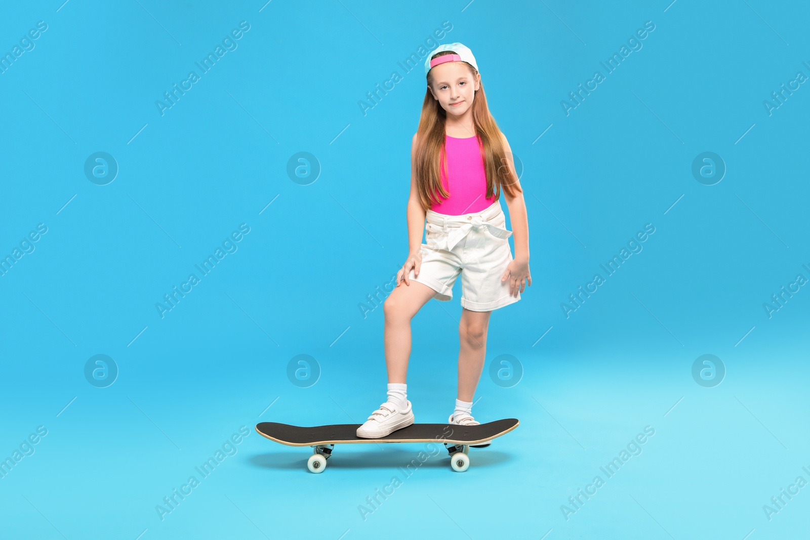 Photo of Little girl with skateboard on light blue background