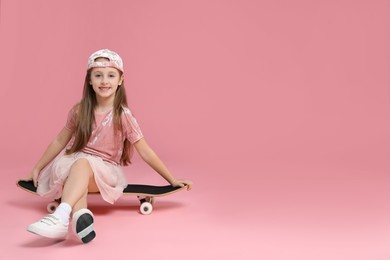 Photo of Little girl with skateboard against pink background, space for text