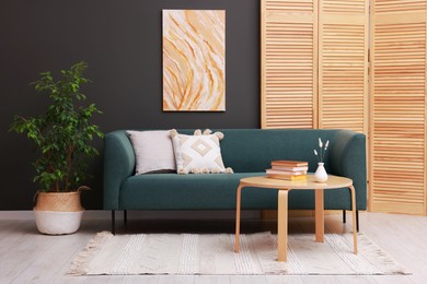 Photo of Soft sofa, houseplant and coffee table near black wall in stylish living room