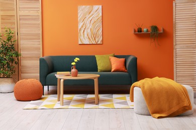 Photo of Stylish living room interior with comfortable sofa near orange wall