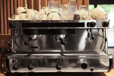 Photo of Professional coffee machine and cups in cafe