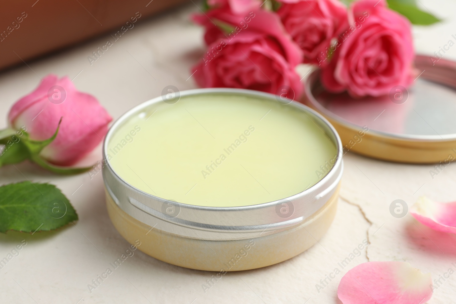 Photo of Natural solid perfume in container and pink roses on white table, closeup