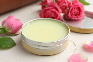 Photo of Natural solid perfume in container and pink roses on white table, closeup